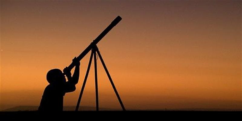 A person looking at a telescope